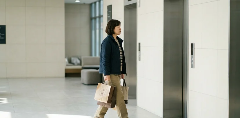상가 로비에서 엘리베이터 쪽으로 걸어 들어오는 여성의 옆모습
