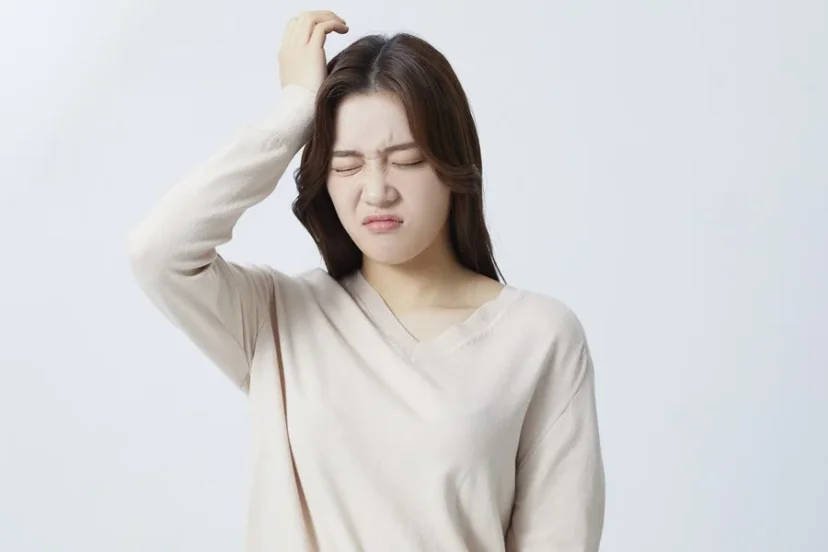 머리를 짚으며 고통스러워하는 여성의 모습