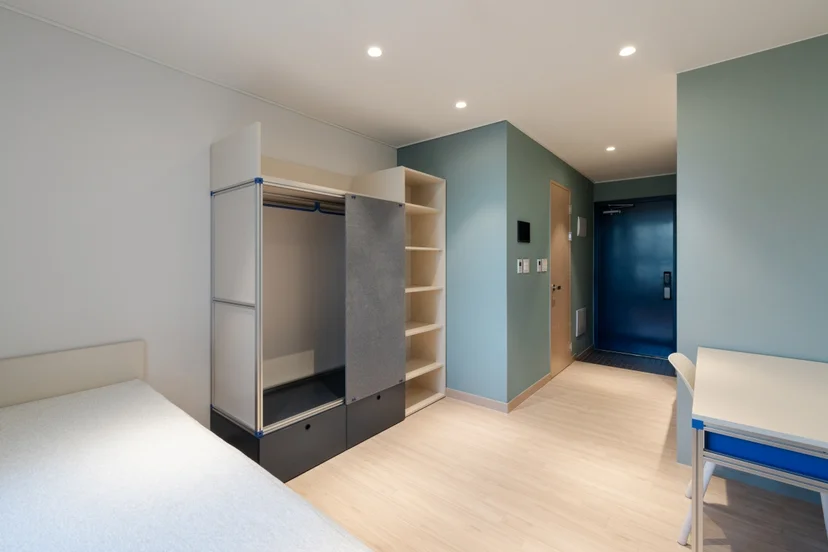 Single room with a bed, desk and open wardrobe at Mangrove Sinchon
