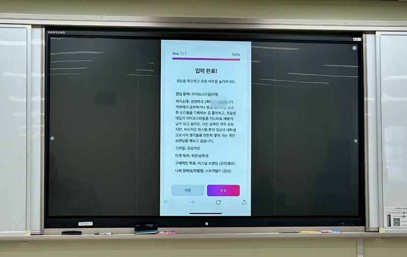 관심 분야, 스타일, 타깃 독자, 목표를 차례로 입력받는 웹앱의 ‘입력 완료’ 화면을 교실 화면에 띄워 시연하는 모습