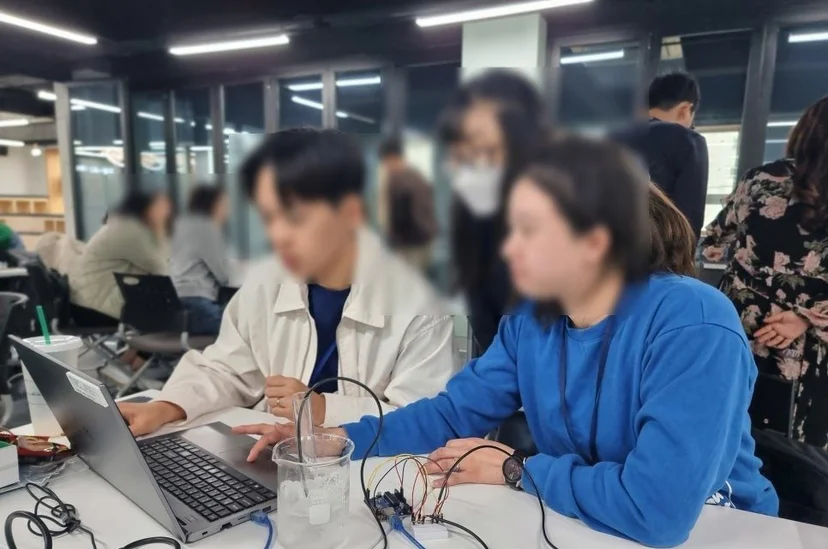 비커 속 물에 방수 온도 센서를 넣고 노트북으로 온도를 기록하는 참가 교사들