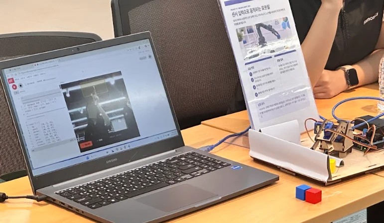 AI 손동작 인식 로봇팔 장치와 제어 화면이 있는 체험 부스