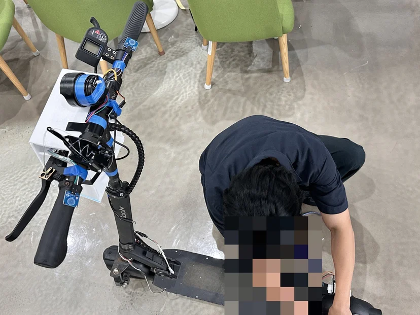 파란 테이프로 센서를 감은 킥보드와 바닥에서 배선을 점검하는 학생