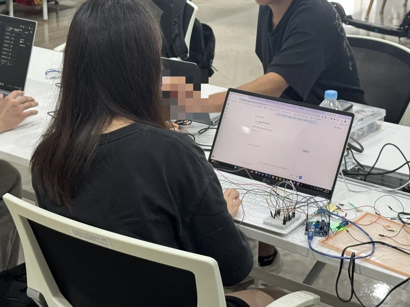 아두이노 회로와 노트북을 함께 놓고 작업하는 학생