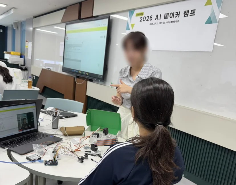 조립한 로봇암과 제어보드를 앞에 두고 설명을 듣는 범박중 학생들