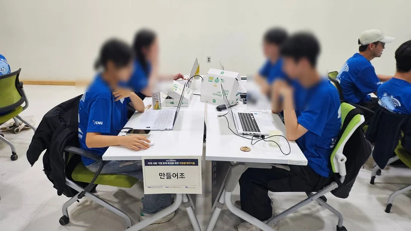 ‘MEAI’, ‘만들어조’처럼 팀 이름 안내판을 세운 테이블에서 논의하는 학생들