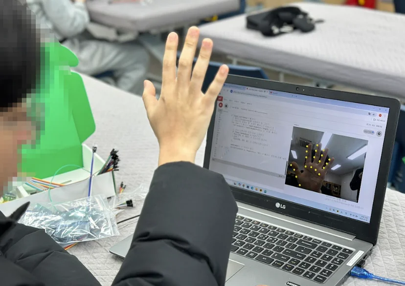 손을 들어 웹캠 화면에서 손 관절 인식을 시험하는 학생