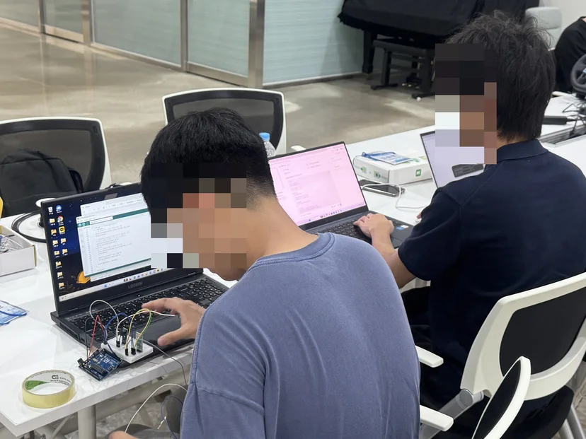 노트북으로 아두이노 코드를 작성하며 브레드보드 회로를 연결하는 학생