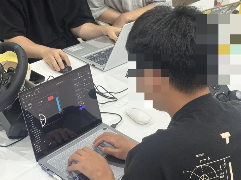 레이싱 휠 옆에서 프로토파이로 운전 화면을 만드는 학생