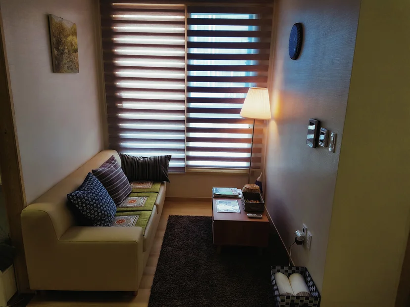 Living corner with a beige sofa, a floor lamp and a low wooden table by the window (Listing ID : 25)