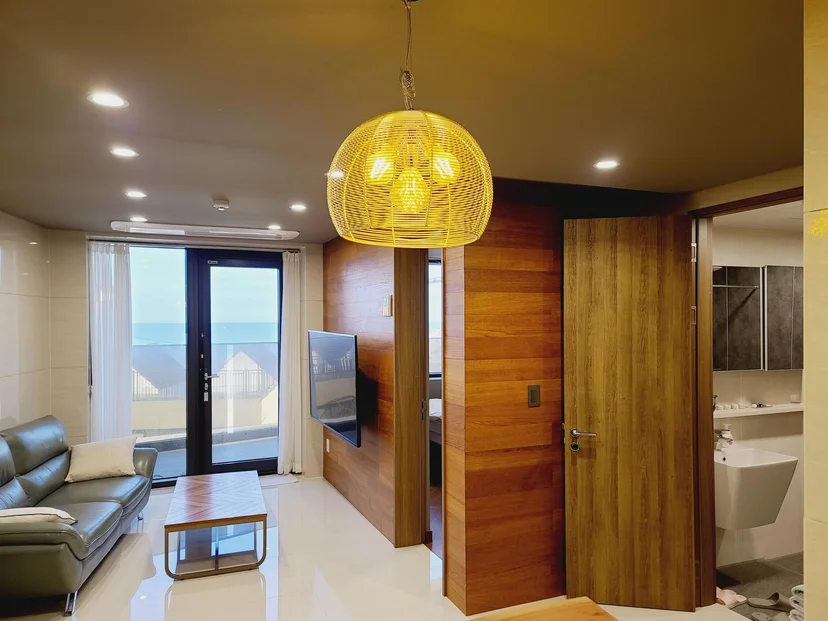 Living room with sofa, TV, and an ocean-view balcony door (Listing ID : 8342)
