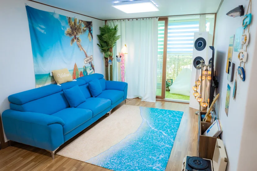 Living room with a blue sofa, tropical decor, and a turntable corner (Listing ID : 4764)