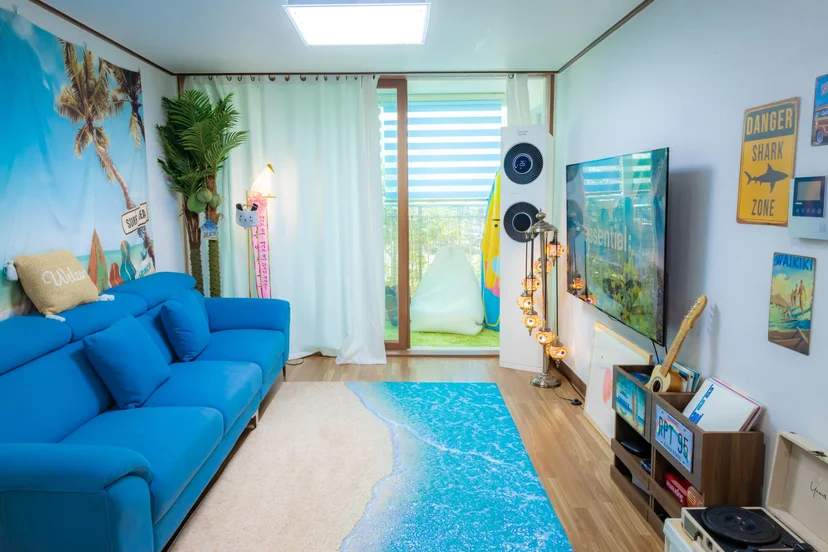 Living room with beach-themed wall art opening onto a turf balcony (Listing ID : 4764)