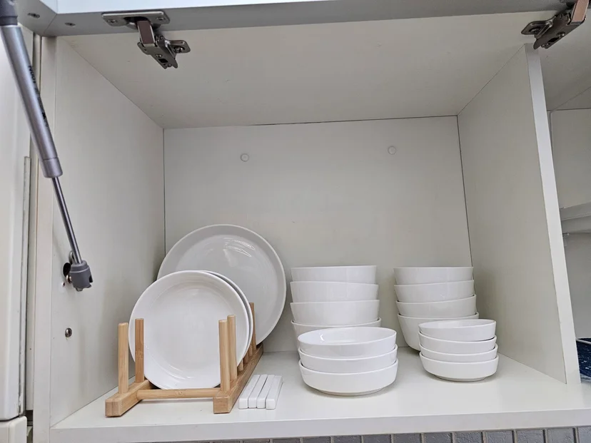 Open kitchen cabinet with white plates and bowls on a bamboo dish rack (Listing ID : 28024)