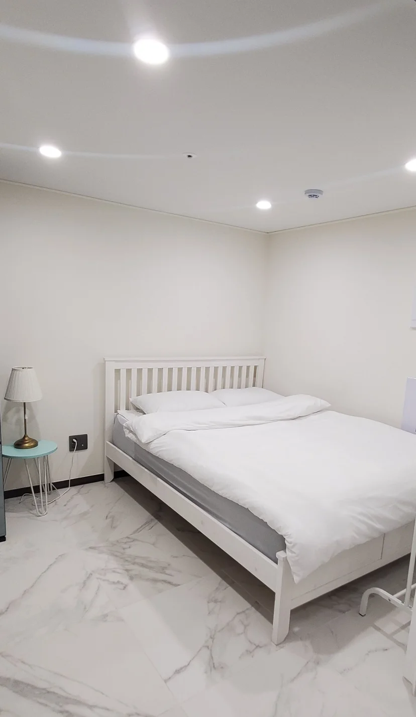 White wooden double bed with a bedside lamp on a marble floor (Listing ID : 26402)