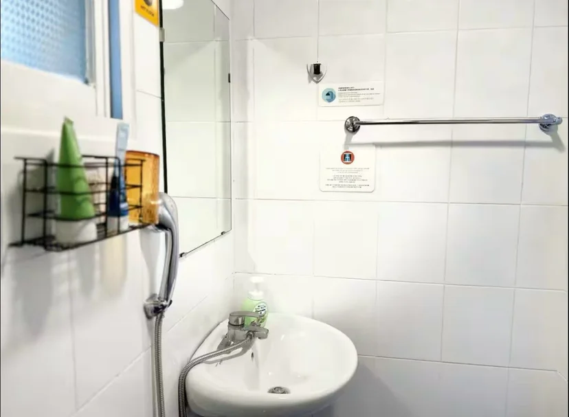 White-tiled bathroom with a wall sink, mirror, and shower hose (Listing ID : 33170)