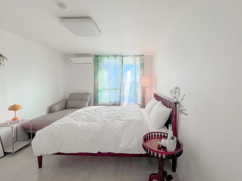 Bright white-toned bedroom with a wood bed frame and lounge chair (Listing ID : 34458)