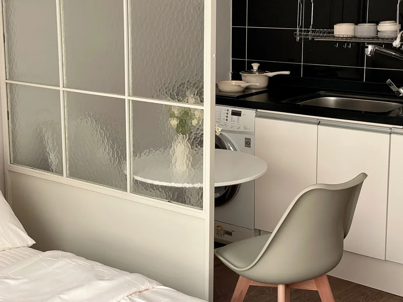 Studio interior with a dining table and a full kitchenette behind a glass partition (Listing ID : 33622)