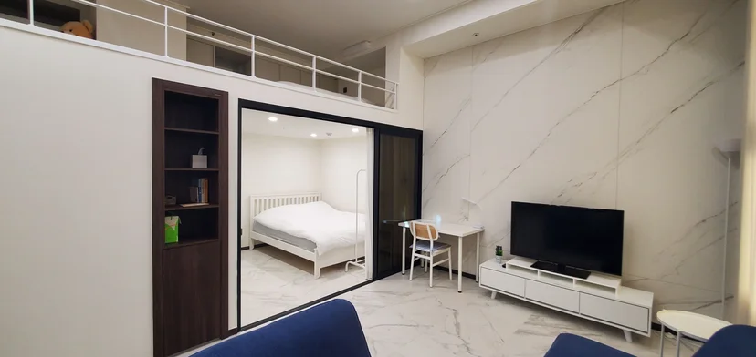 Bright duplex living room with TV and a glass-walled bedroom beyond (Listing ID : 26402)