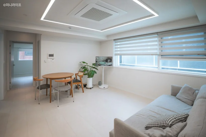Bright white living and dining area with wood table and gray sofa (Listing ID : 32497)