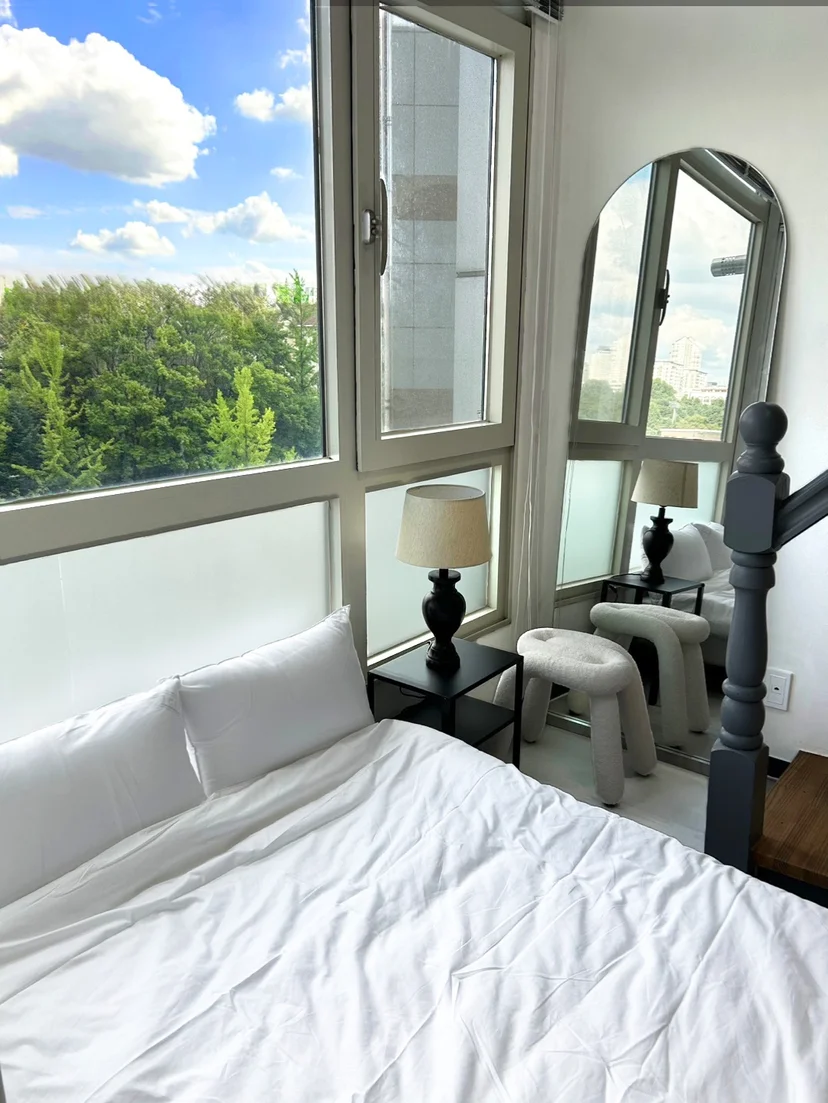 Bedroom with a bed, arched mirror, and a bright window (Listing ID : 30632)