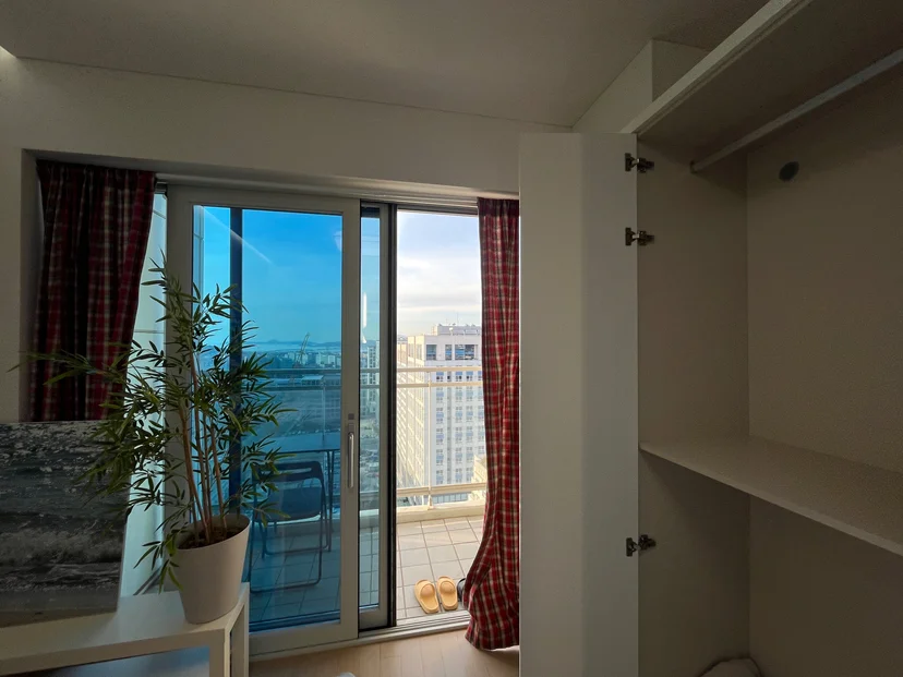 Open wardrobe beside the balcony door with a distant harbor view (Listing ID : 35960)