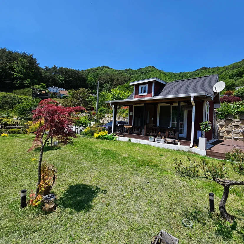산 능선을 배경으로 한 독채 외관과 마당