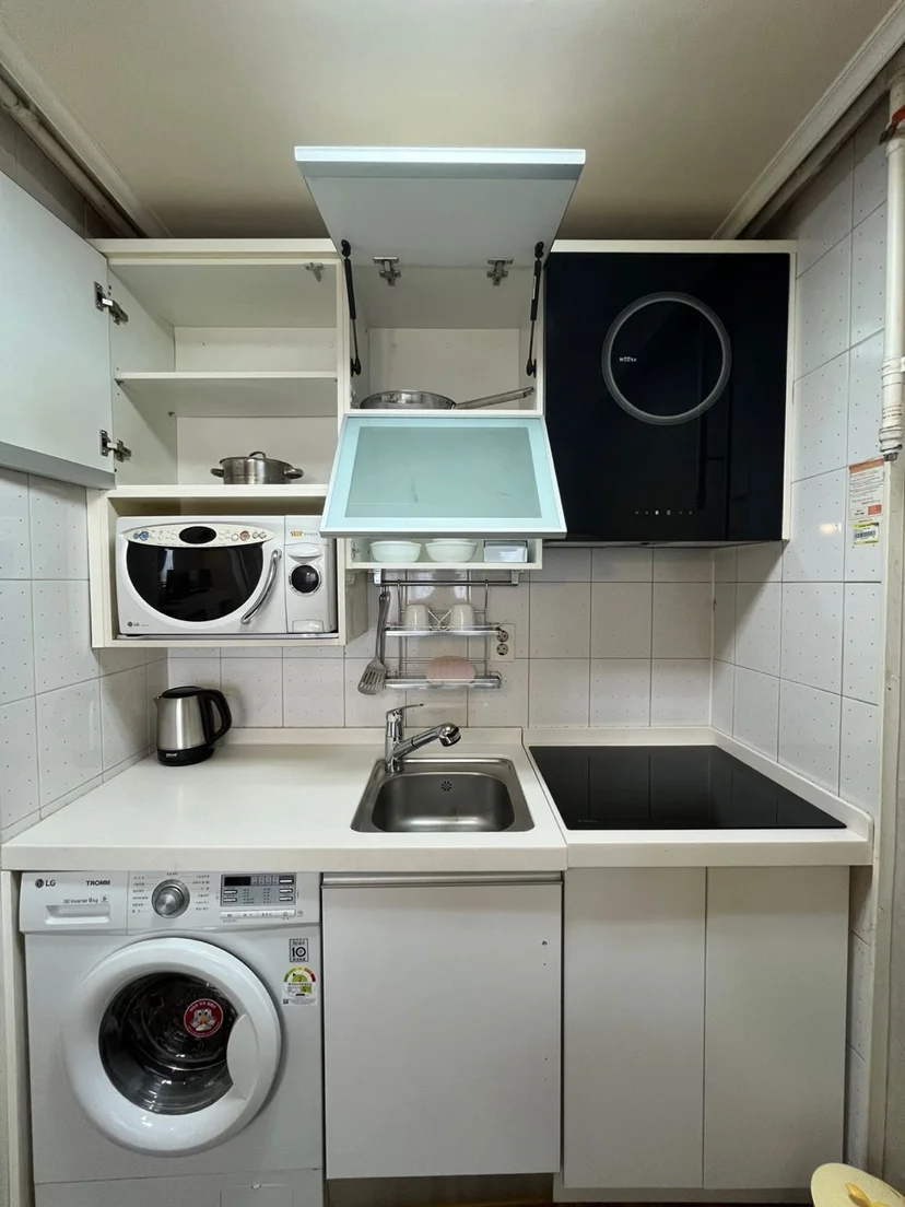 Compact in-unit kitchenette with induction cooktop, microwave, sink, and washing machine (Listing ID : 34007)