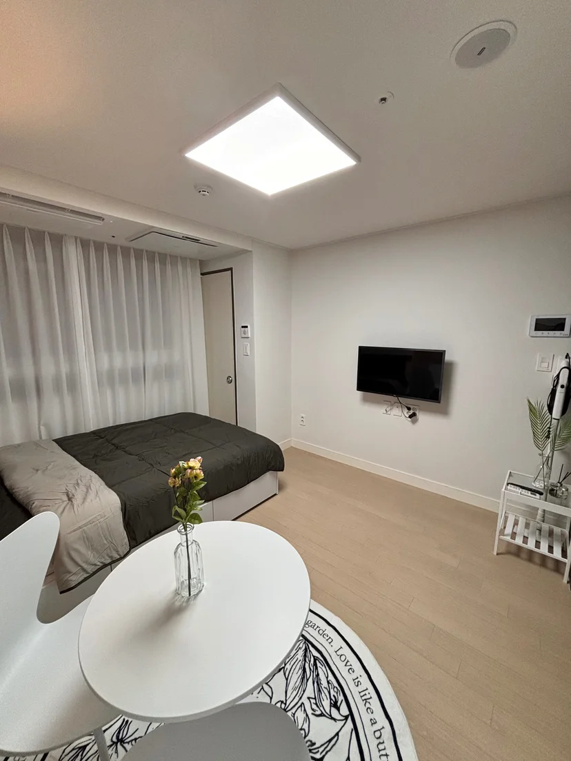 Studio interior with bed, wall-mounted TV, and round dining table (Listing ID : 30036)