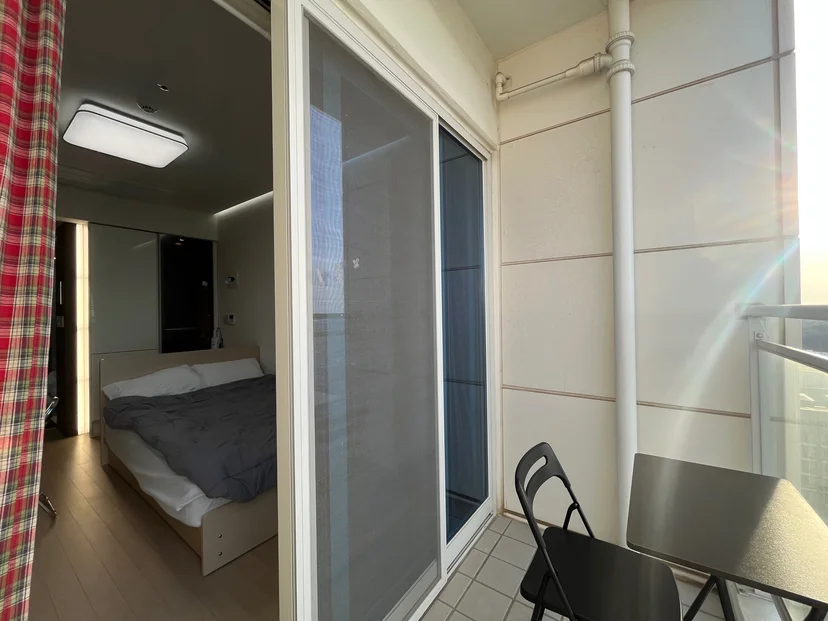Bed alcove beside the balcony with a folding chair and table (Listing ID : 35960)