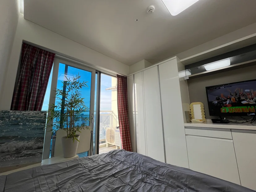 Bed facing the balcony door with a bamboo plant and wall TV (Listing ID : 35960)