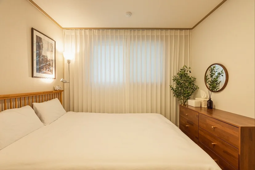 Bedroom with a wooden headboard and sheer curtains (Listing ID : 32182)