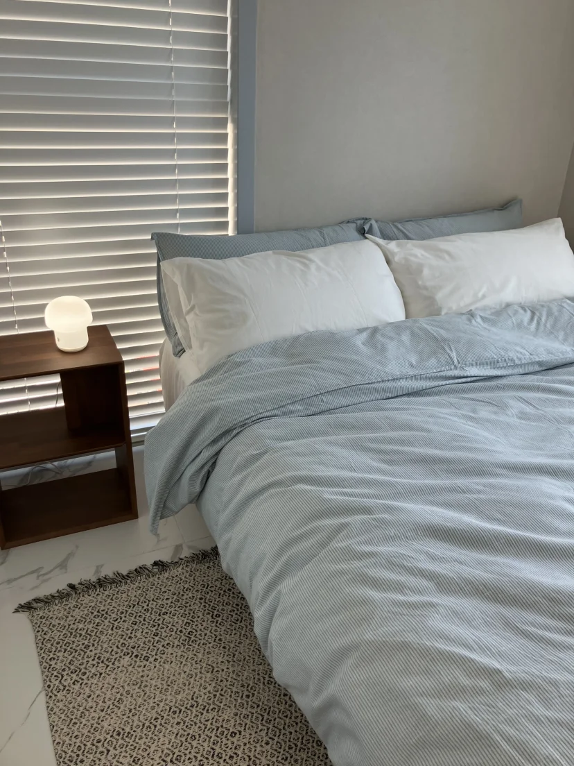 Double bed with a striped duvet beside a curtained window (Listing ID : 25414)