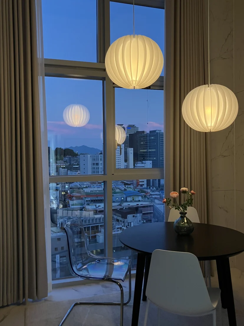 Dining table by a floor-to-ceiling window with a city and mountain view at dusk (Listing ID : 25414)