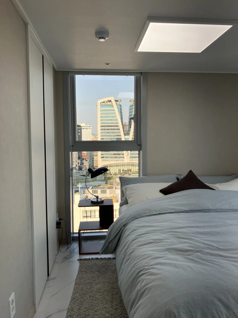 Bedroom with a double bed and a large window framing the Seoul skyline (Listing ID : 25414)