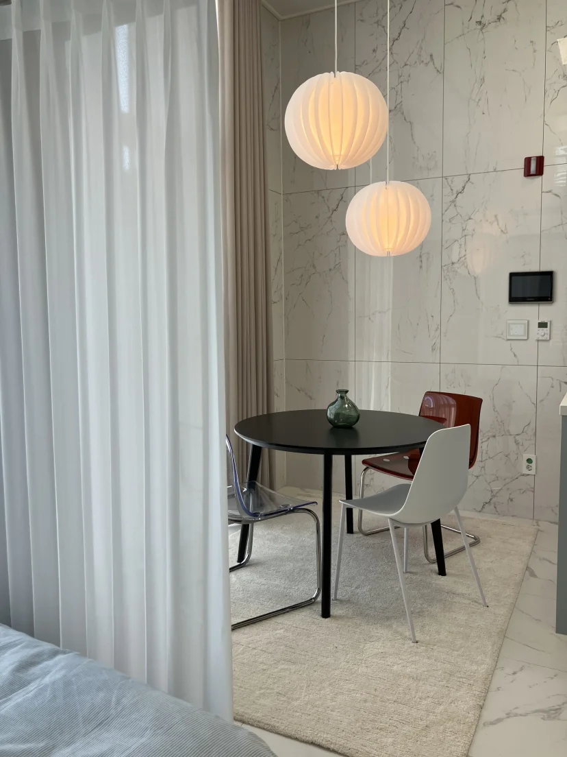 Dining nook with a round table, globe pendant lights and a marble wall (Listing ID : 25414)