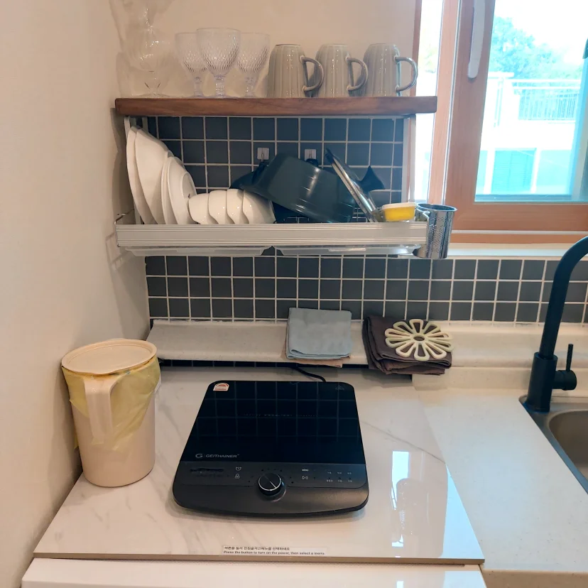 Kitchenette with portable induction cooktop and dish rack by window (Listing ID : 43593)