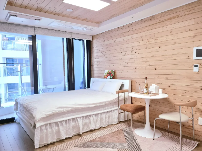 Wood-panelled studio with a double bed and a small cafe table by the balcony (Listing ID : 12257)