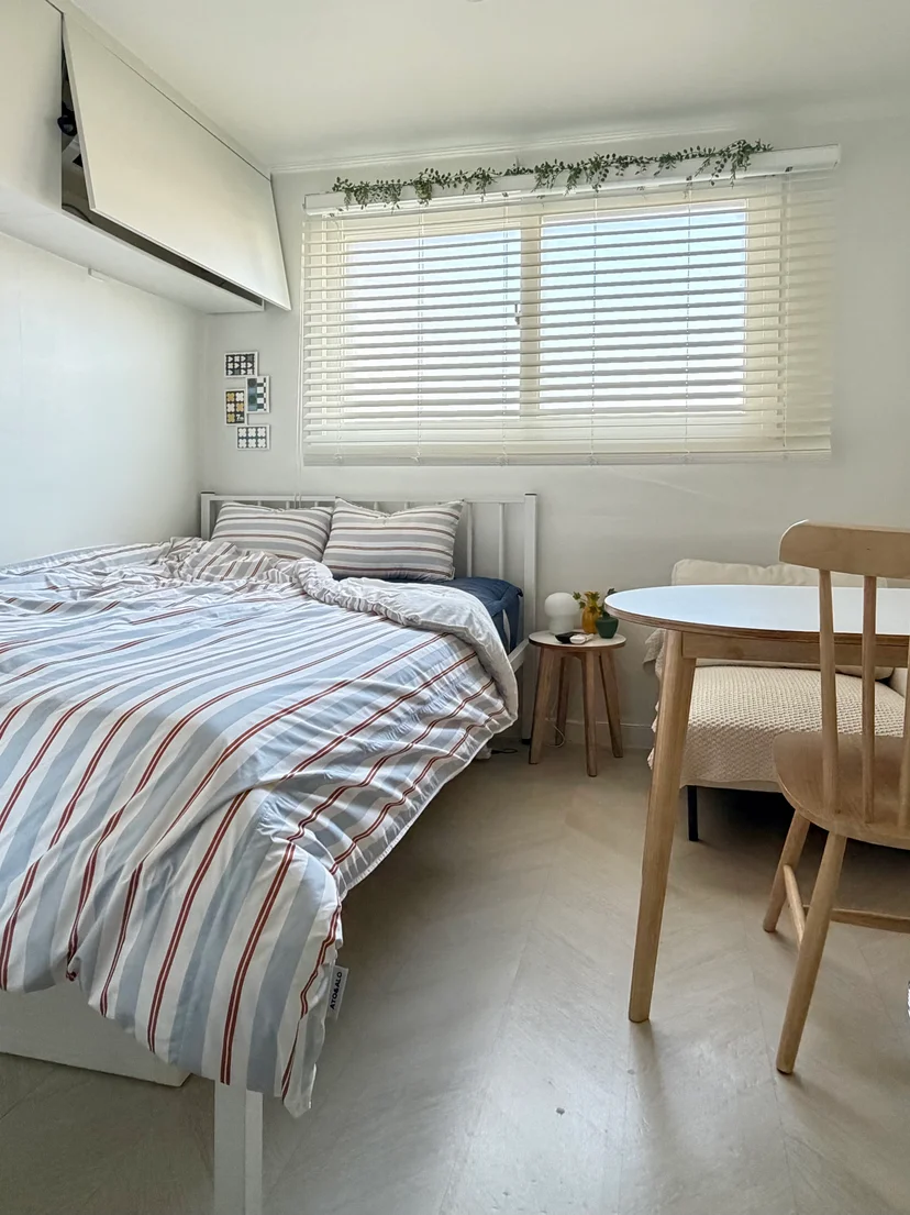 Striped double bed and round table under a bright window (Listing ID : 35470)