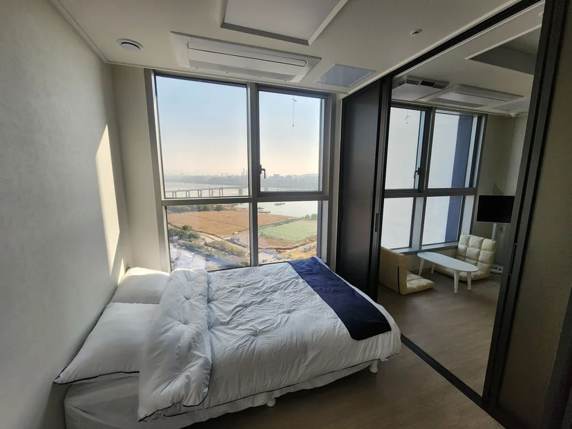Bedroom with a double bed and a river-view window, glass sliding door to the living area (Listing ID : 32655)