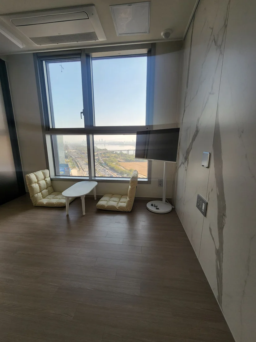 Living corner with a marble accent wall, a standing TV and a river-view window (Listing ID : 32655)