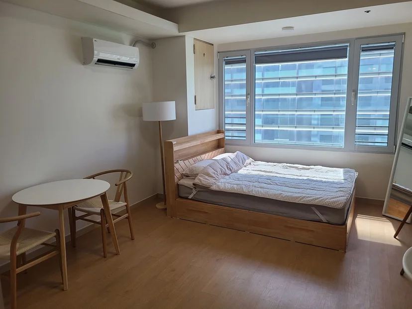 Studio with a wooden bed, dining table and city-view windows (Listing ID : 26409)