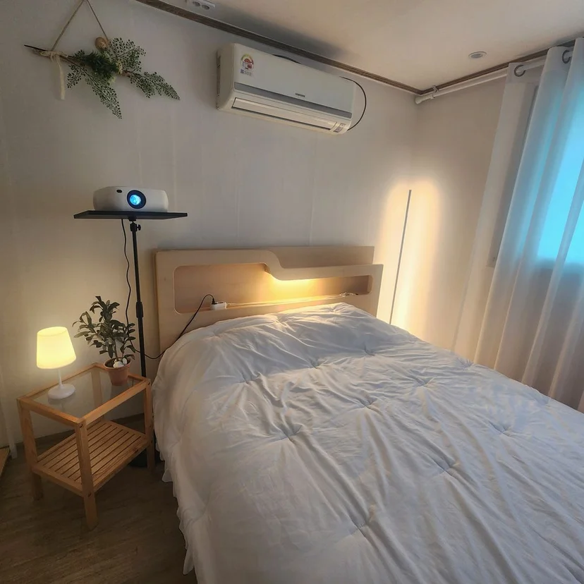Bedroom with a wall-mounted air conditioner, wood headboard, and double bed (Listing ID : 25853)