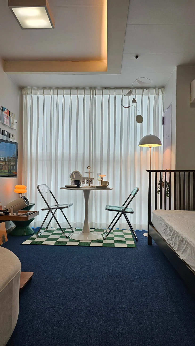 Studio interior with round dining table and chairs by sheer-curtained window (Listing ID : 28024)