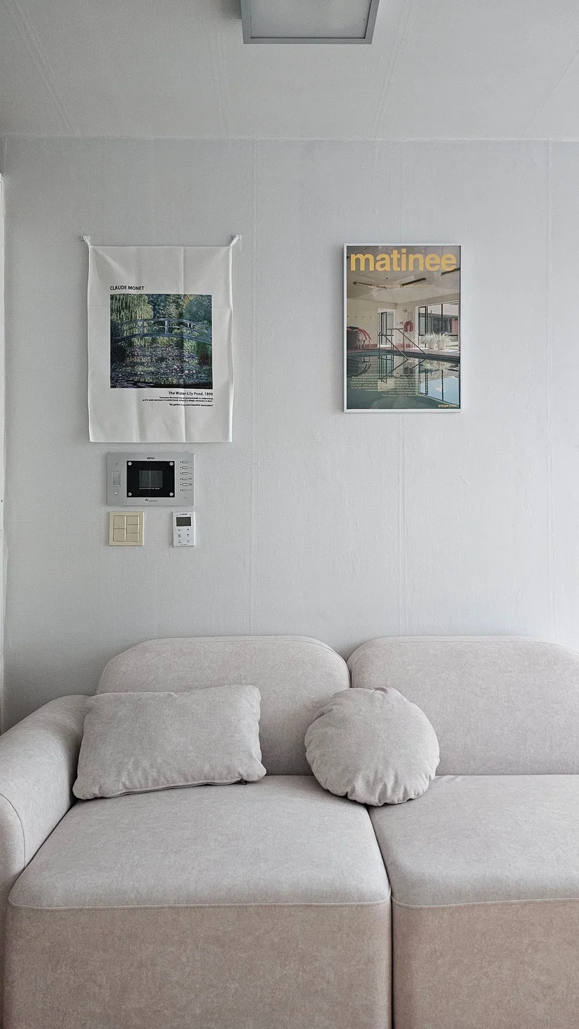 Beige fabric sofa with art posters on a white wall in the furnished studio (Listing ID : 28024)