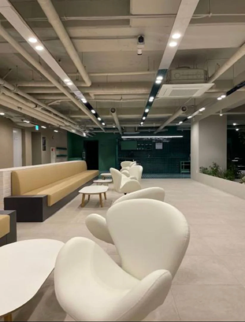 Shared lounge with white pod chairs and bench seating in the building (Listing ID : 30596)