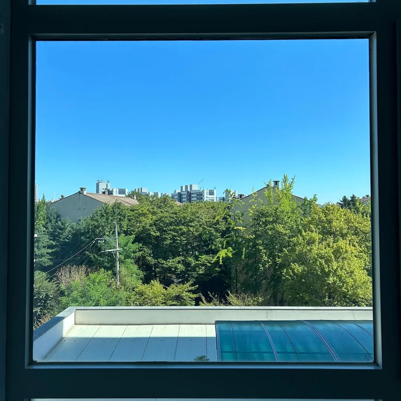 Window view over a rooftop terrace, trees, and the city skyline (Listing ID : 30632)