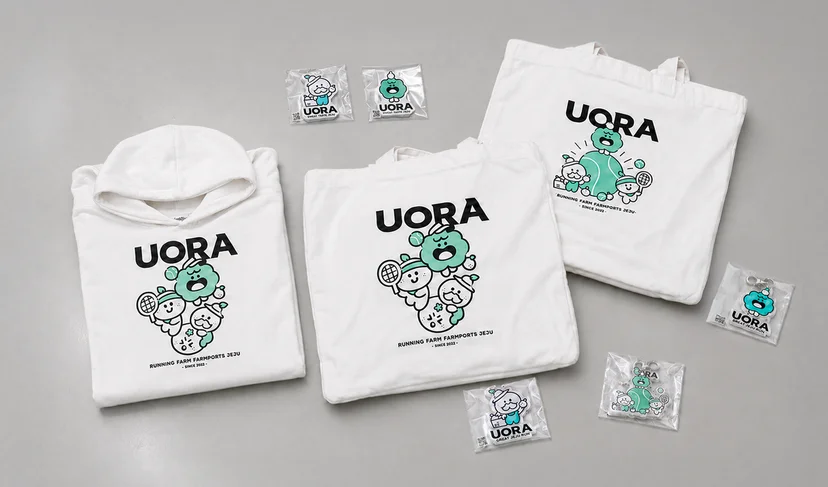 마플 단체 굿즈 – UORA 캐릭터 그래픽을 인쇄한 화이트 후드티와 에코백, 아크릴 키링으로 구성한 브랜드 굿즈 세트 이미지