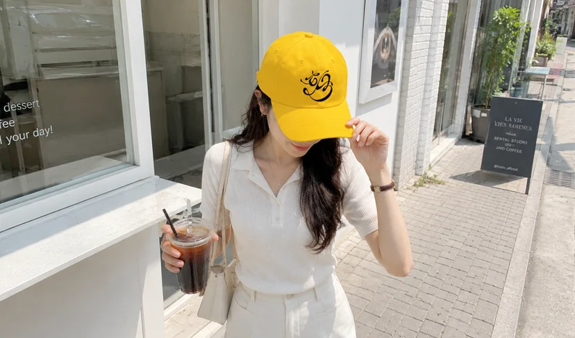 마플 베이직 야구모자 - 브랜드 로고를 자수로 새긴 옐로우 야구모자를 야외에서 착용한 이미지