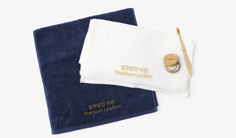 마플 송월 호텔타올 40수 – 기업명을 자수로 새겨 제작한 네이비·화이트 타올 2장을 펼쳐 놓은 이미지